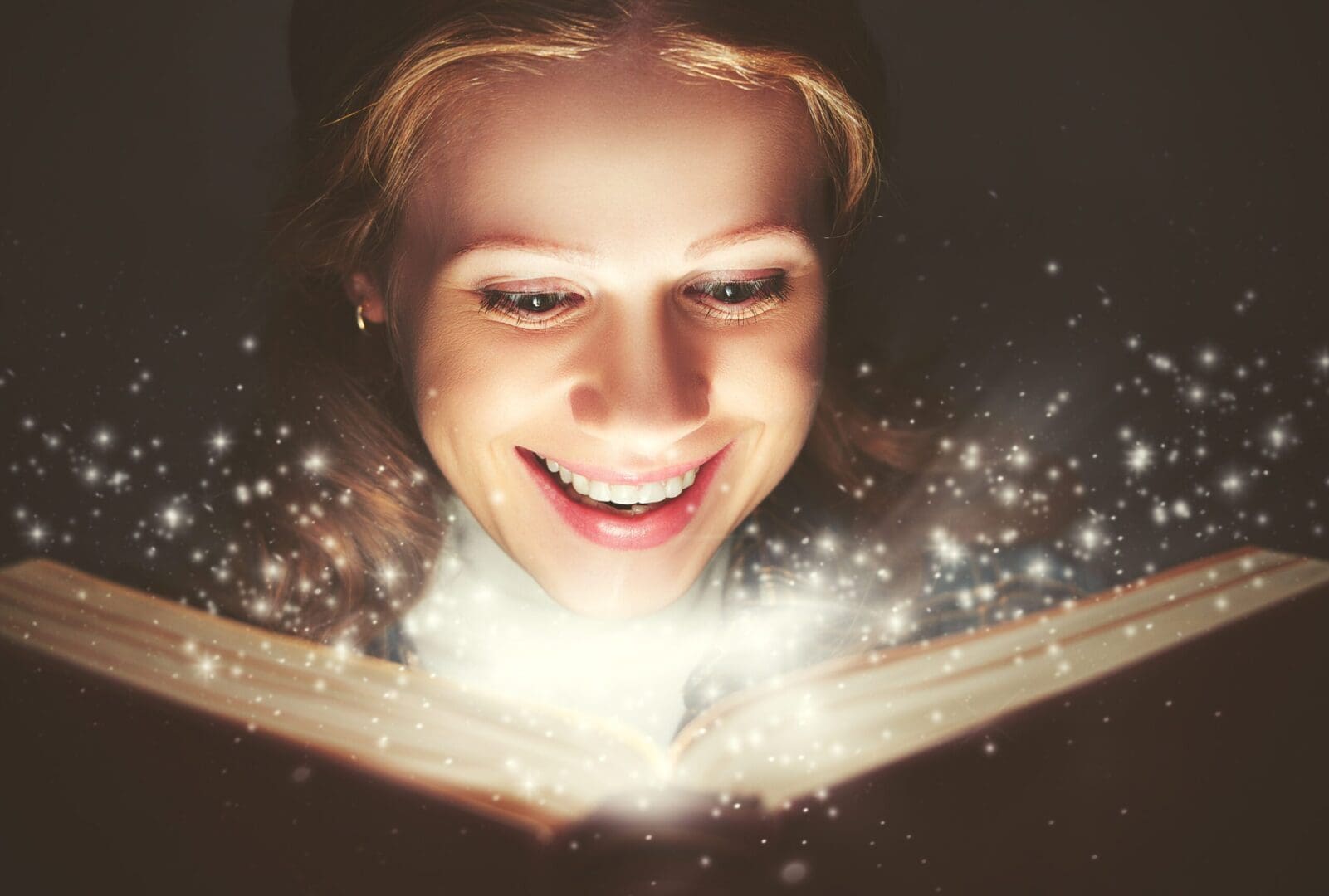A woman joyfully discovers magic from an illuminated book.