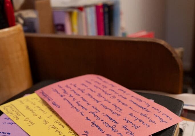 Handwritten sticky notes on notebook at desk