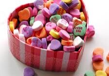 Heart-shaped box filled with colorful conversation heart candies.